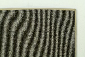 This black and tan rug is made of tufted wool and finished at 100"x34" with a narrow cotton binding