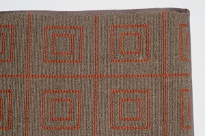 This green luxury wool rug has an orange geometric pattern and is finished at 93"24" with narrow cotton binding.