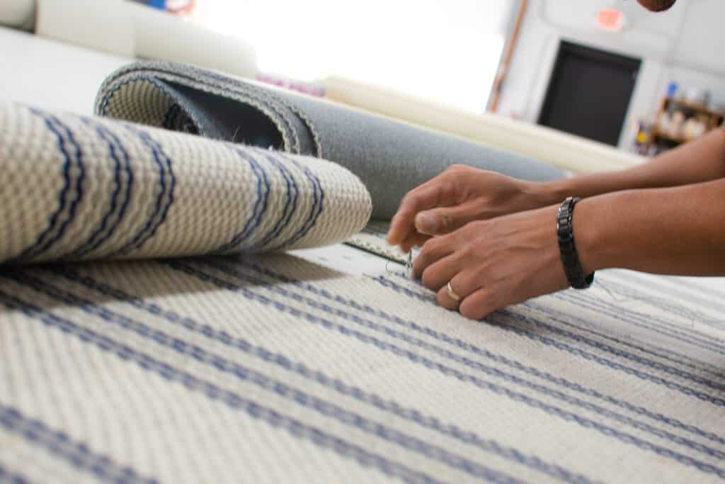 Fabricator hand stitching a custom stair runner project.