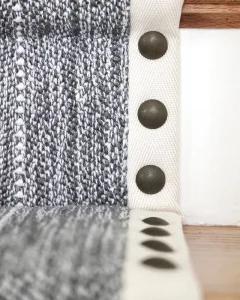 Black and white striped carpet with a cream wide binding and nail heads as a decoration installed as a stair runner.