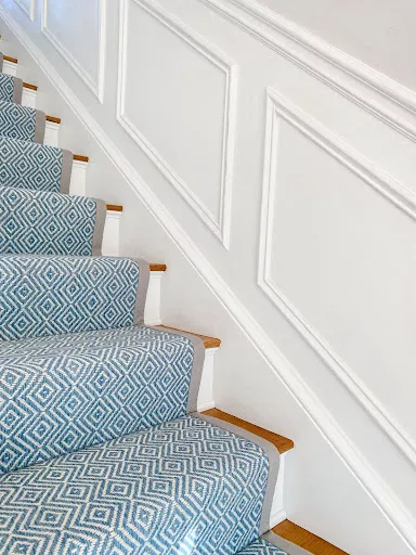 Blue and white diamond pattern carpet with a wide binding fabricated and installed as a stair runner.
