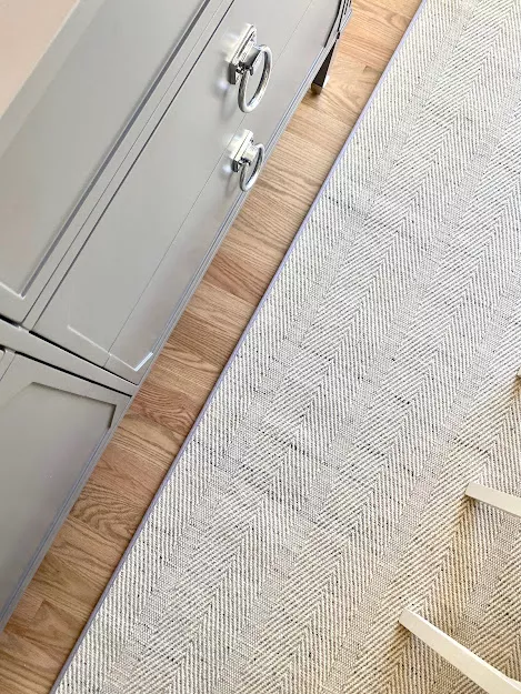 Final details of a rug with a herringbone style with light colors installed on a room.
