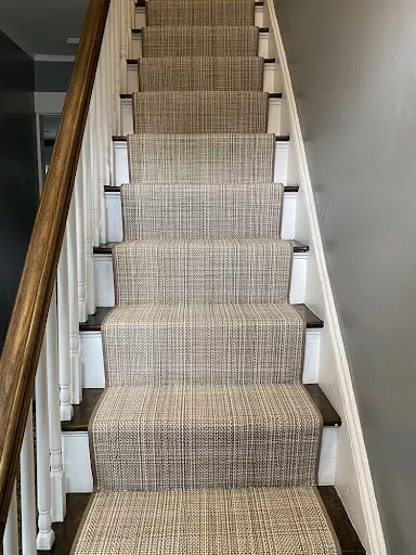 Textured carpet design with a narrow binding fabricated and installed as a stair runner.