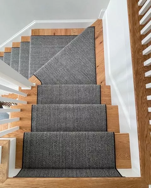 Black carpet with herringbone style and narrow binding fabricated and installed as a stair runner.