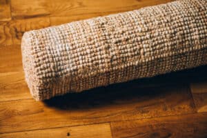 New rolled jute rug with chunky texture on oak flooring, natural fiber carpet, eco friendly home interior concept, shallow DoF