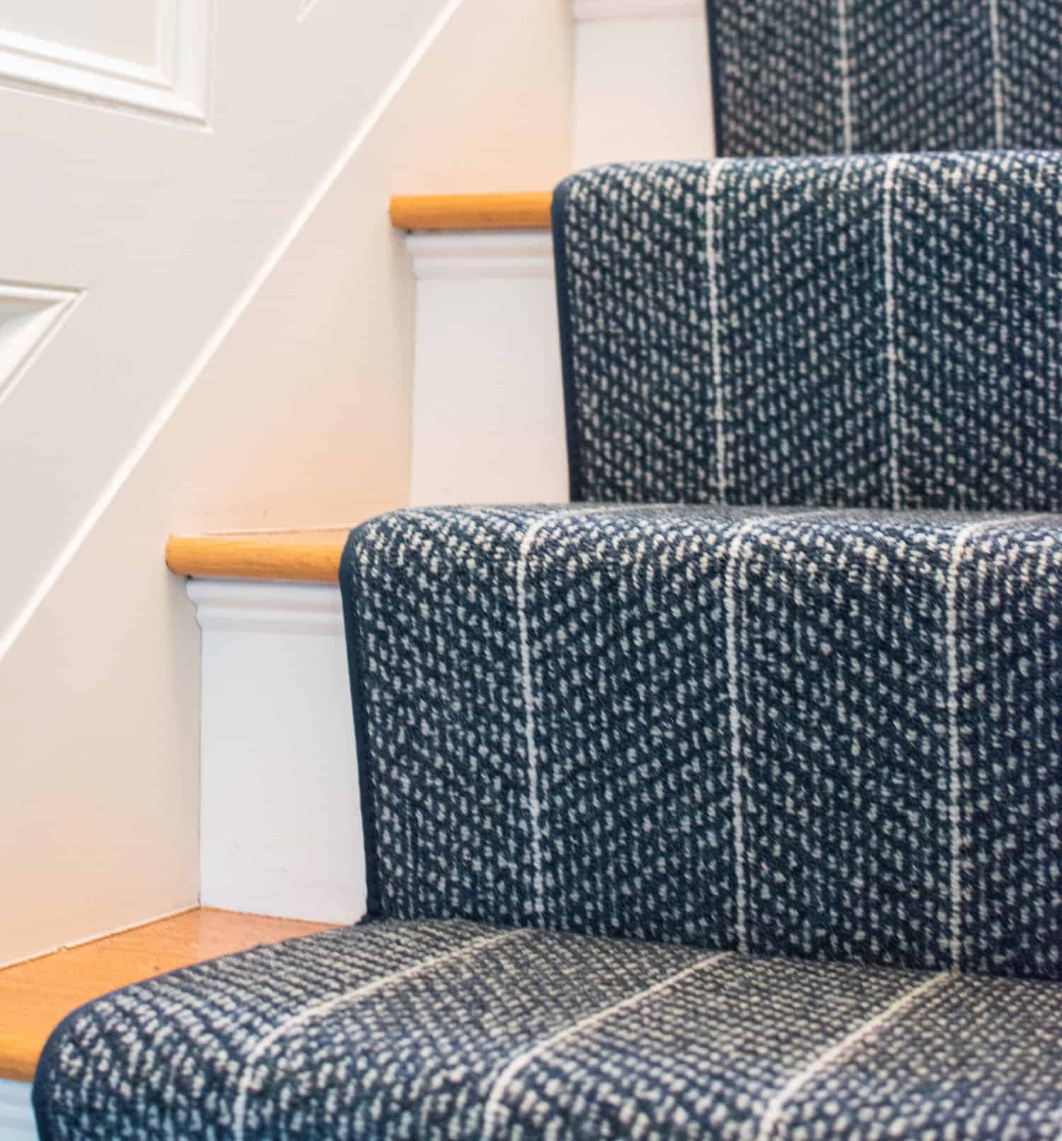 This is a navy blue and white striped carpet that is fabricated and installed as a stair runner