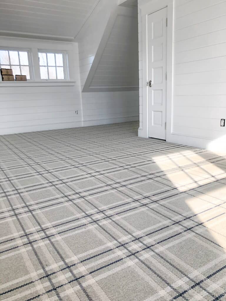This is a gray with white, beige and navy blue striped, wall-to-wall carpet with flat woven plaid style.
