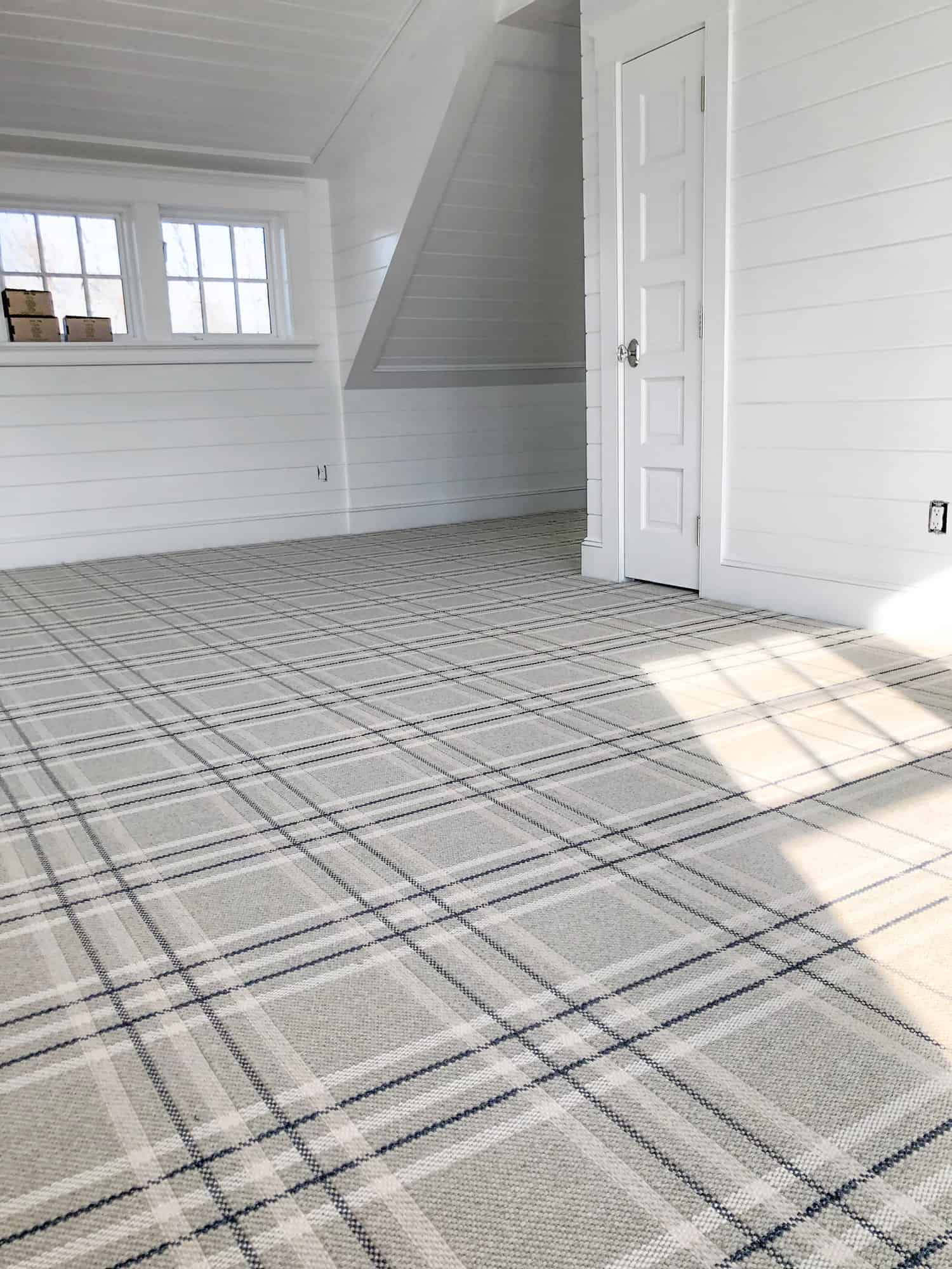 This is a gray with white, beige and navy blue striped, wall-to-wall carpet with flat woven plaid style.