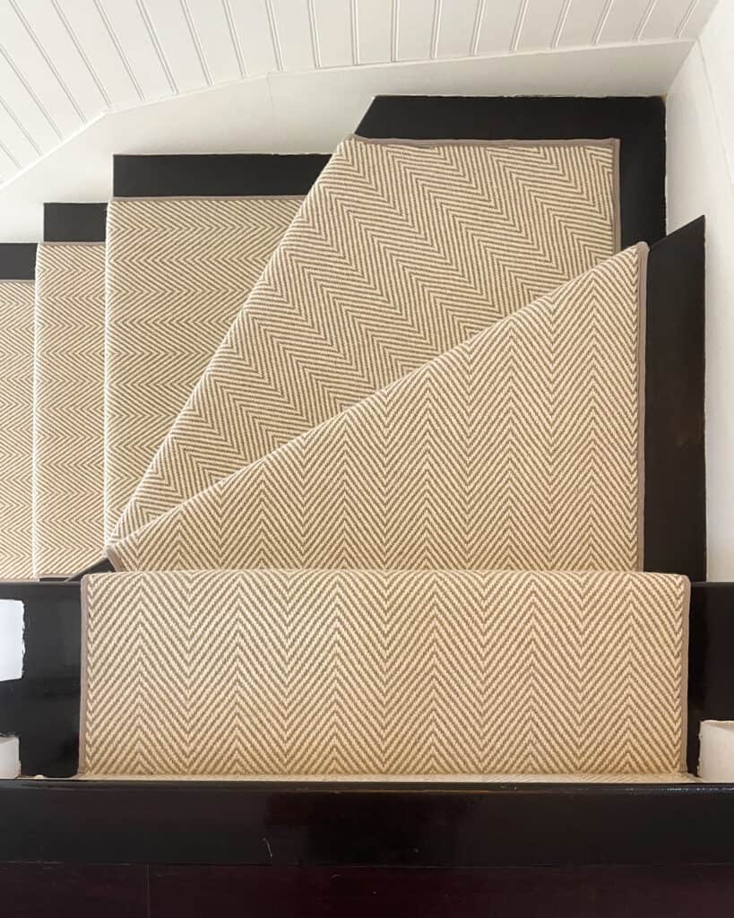 Looking down on a wool rug stair runner. Black stairs with a neutral color