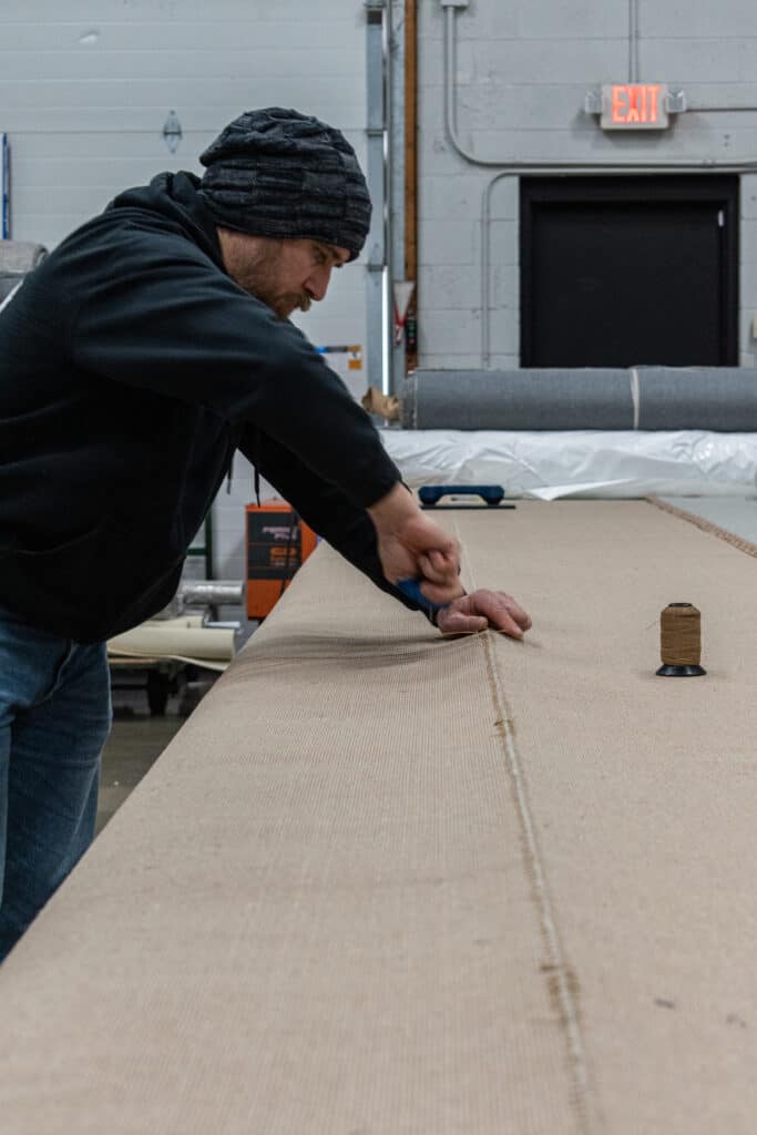 Broadloom carpet style is being seamed by hand.