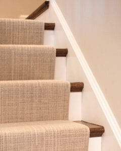Neutral color Stair runner with a narrow cotton binding and installed using the 'waterfall' method.