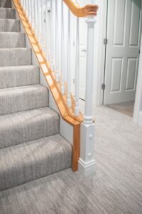 basement with a neutral carpet flooring and continuing up the stairs